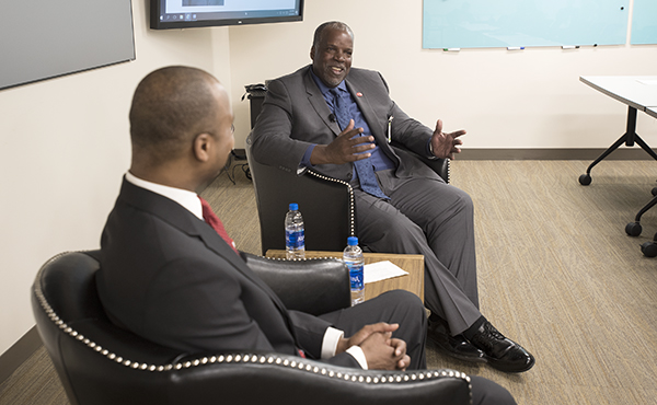 2 men sitting in chairs talking